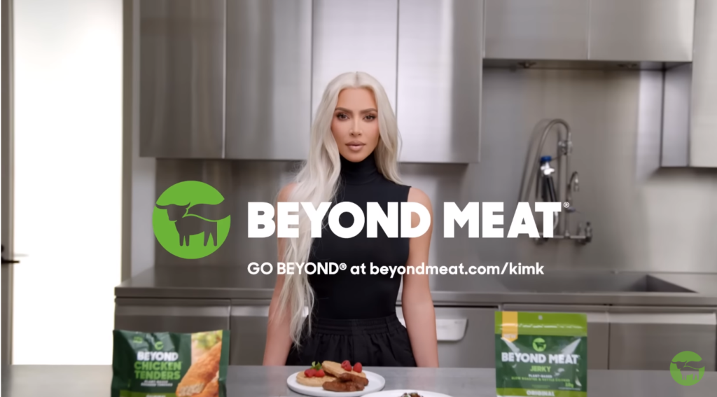 Kadr ze spotu reklamowego Beyond Meat przedstawiający Kim Kardashian i logotyp marki